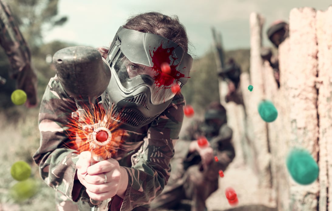 Portrait of young woman in full gear playing paintball on open b